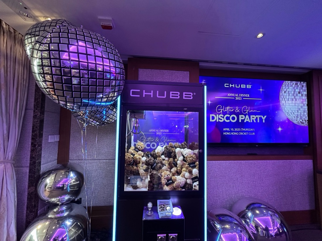 酒店宴會廳內的公司周年晚宴，訂製品牌夾公仔機放在舞台旁，機內載滿毛公仔